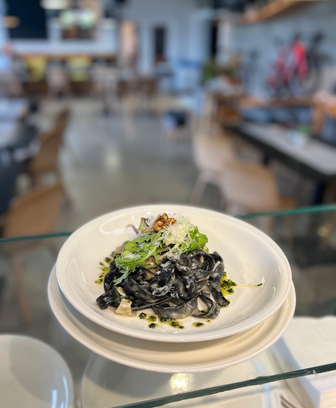 Tagliatelle nero servírované v bistru, v pozadí vystavená kola